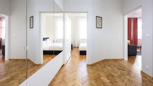 Una camera d'albergo moderna con pavimento in parquet, un grande specchio e un letto con biancheria bianca.