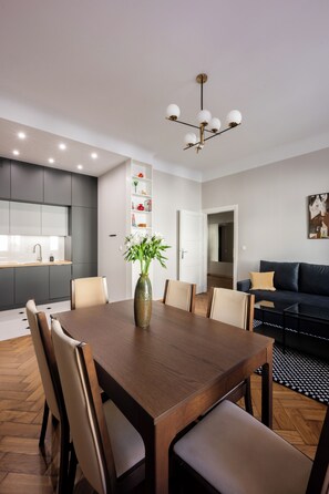 Un comedor moderno con una mesa de madera, sillas, un jarrón con flores y una araña.