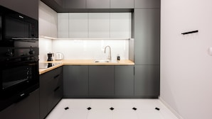 Una cucina moderna con mobili scuri, un piano di lavoro in legno e un lavello in acciaio inossidabile.