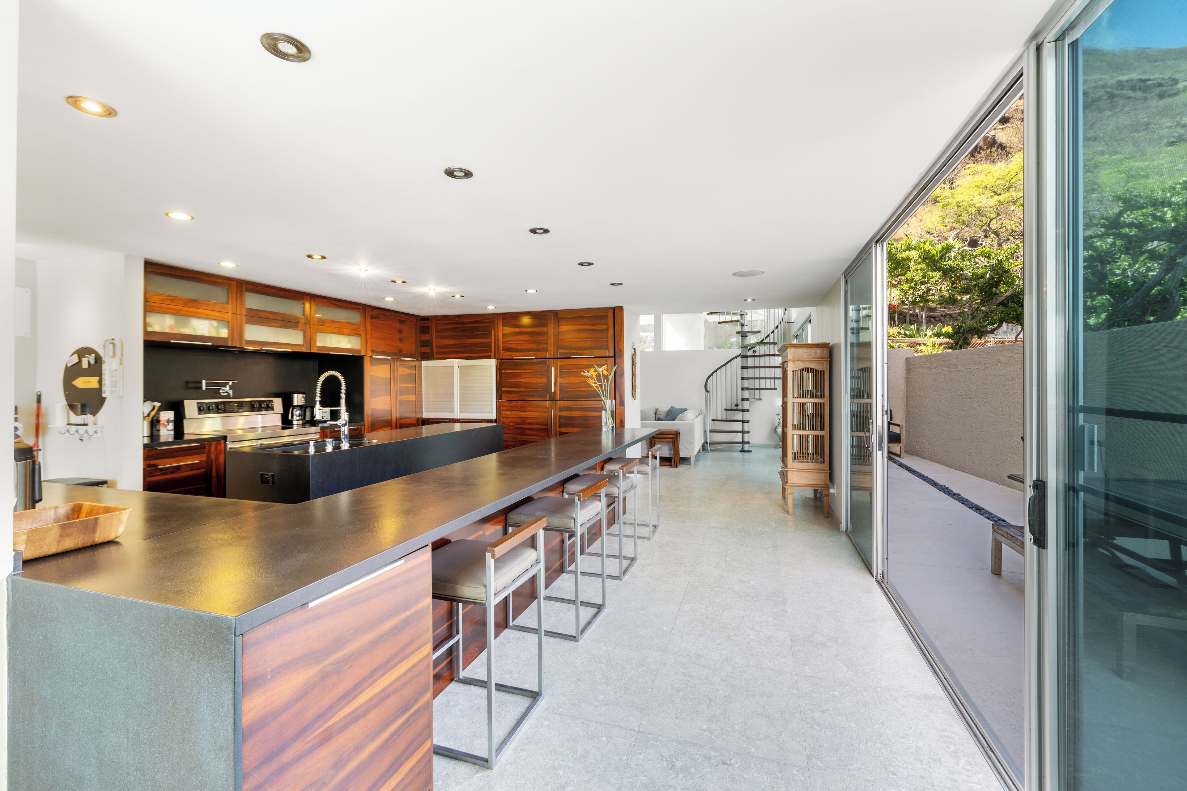 Une cuisine moderne dotée d’un grand îlot central, de meubles en bois et offrant une vue sur l’extérieur.