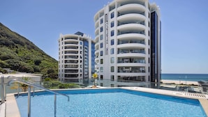 A modern hotel with a pool, surrounded by lush greenery and a clear view of the ocean. - Ocean Eleven Mt Maunganui (Mount Maunganui)