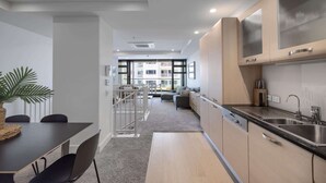 A modern kitchen with a dining area, a staircase leading to an upper floor, and large windows providing natural light. - Ocean Eleven Mt Maunganui (Mount Maunganui)