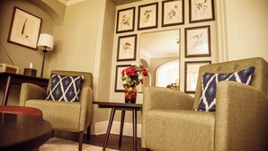 A living room with two armchairs, a small table, and a vase of flowers. - The Falcon Cottages (Northampton)