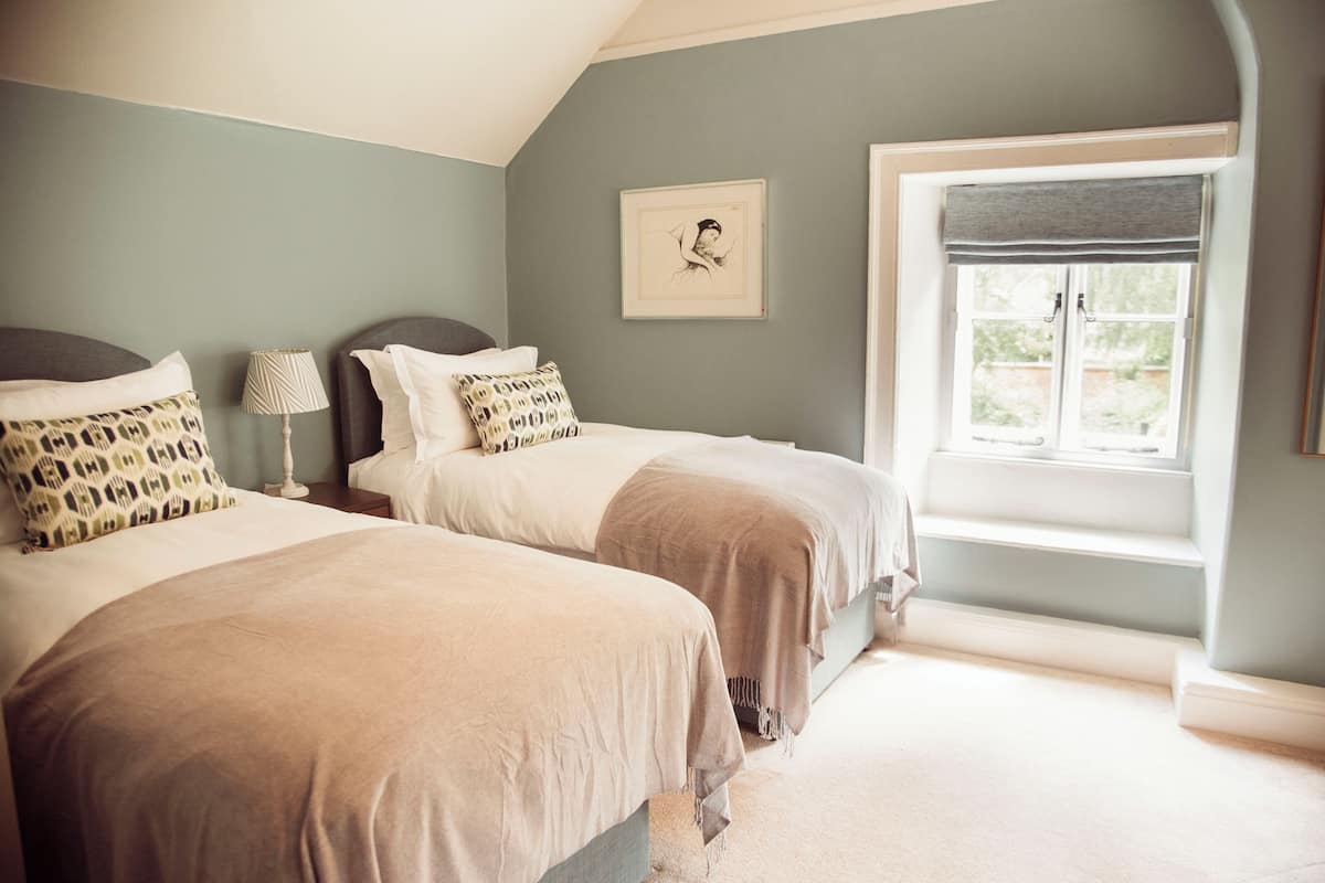 A bedroom with two beds, a window with a view, and a framed picture on the wall.