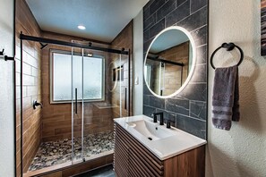 A modern bathroom with a glass shower enclosure, a vanity with a mirror, and a towel rack. - Luxury on Ocean Drive - Sleeps 28 (Corpus Christi)