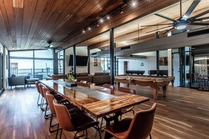 A spacious room with a long wooden table, leather chairs, a pool table, and a ceiling fan. - Luxury on Ocean Drive - Sleeps 28 (Corpus Christi)