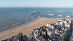 Een kuststadsgezicht met een strand, gebouwen en een vuurtoren.