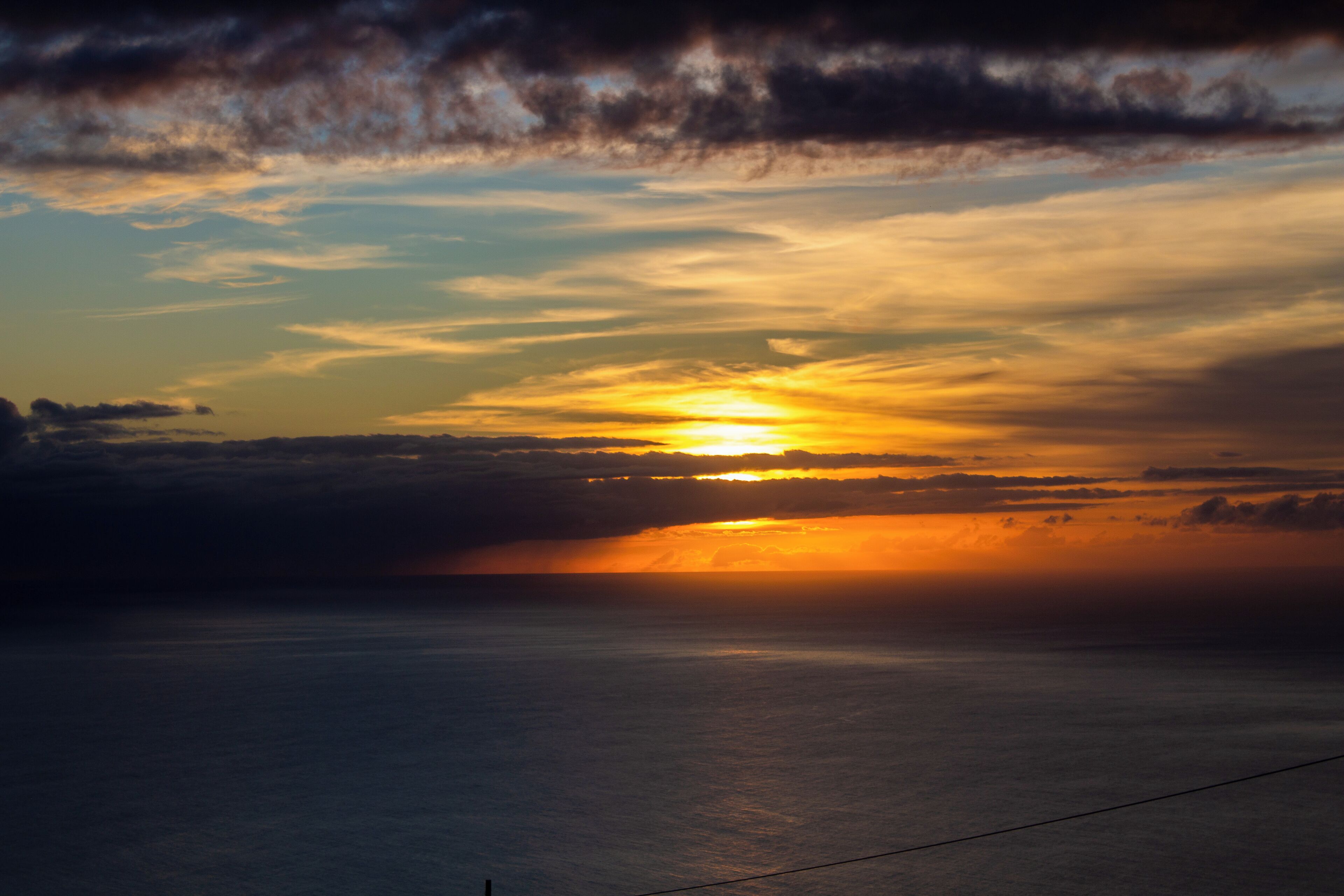 Ein Sonnenuntergang über einem Gewässer bei klarem Himmel.
