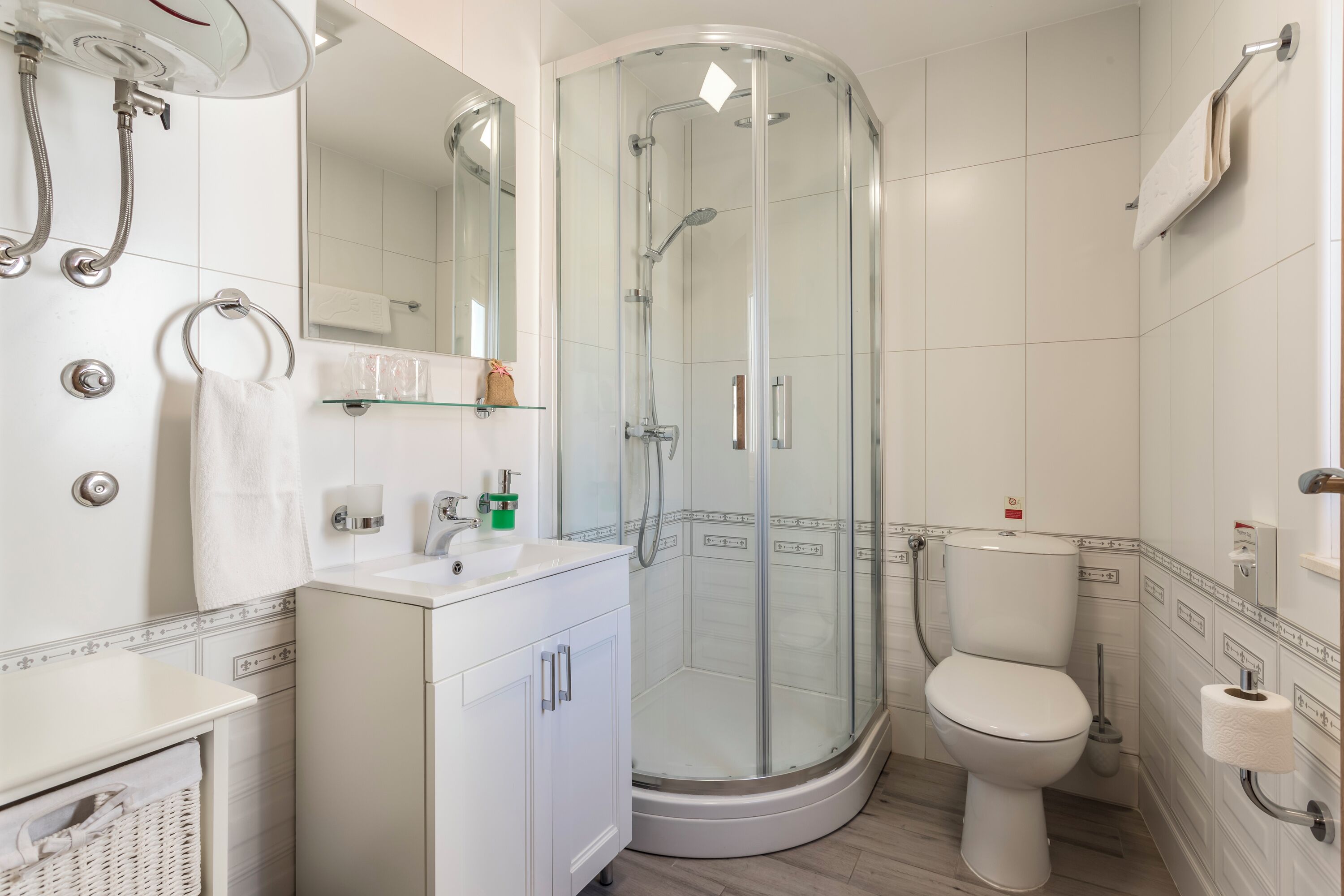 A modern bathroom with a glass-enclosed shower, a toilet, and a sink with a mirror above.