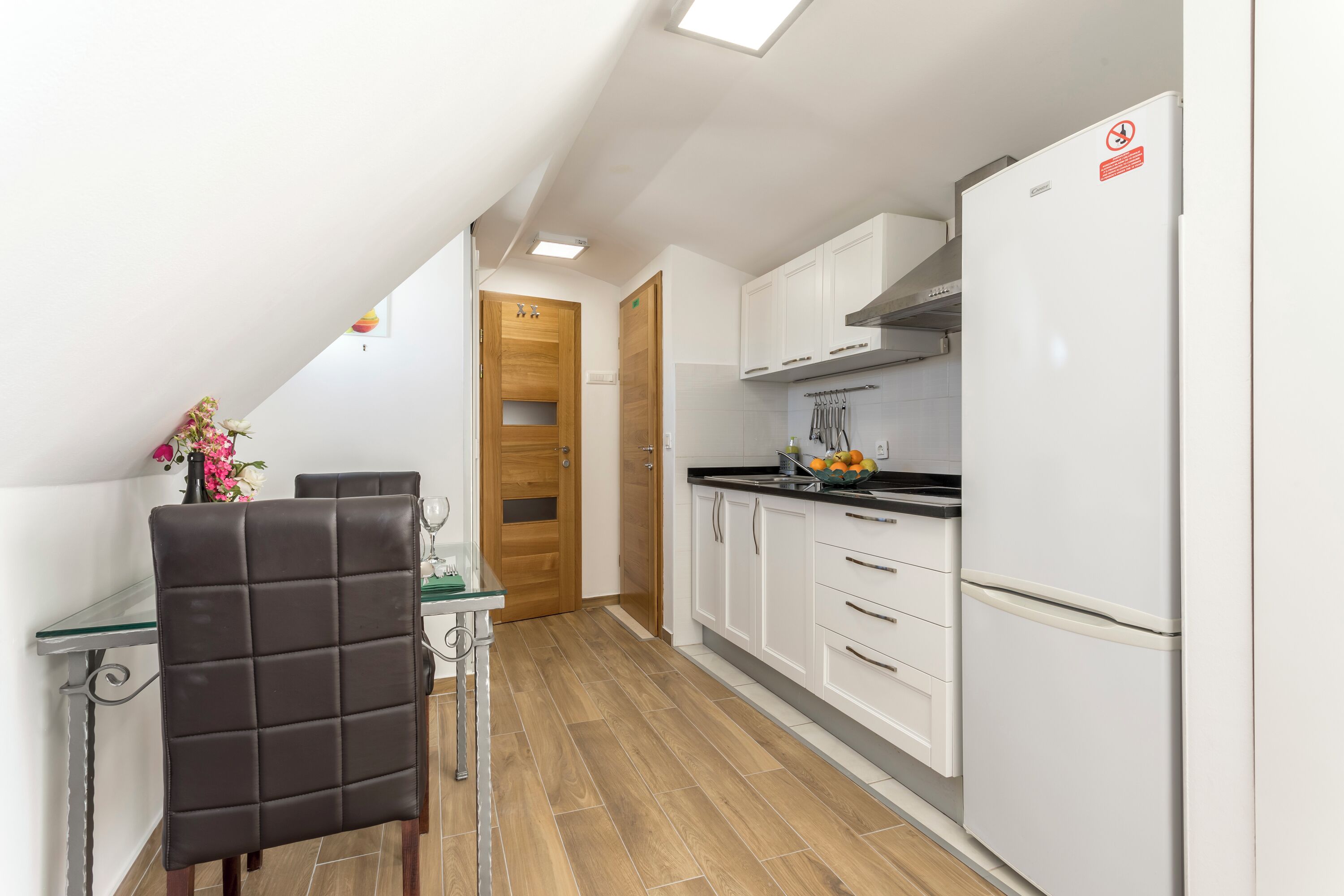 A compact kitchen with white cabinets, a black countertop, and a white refrigerator.