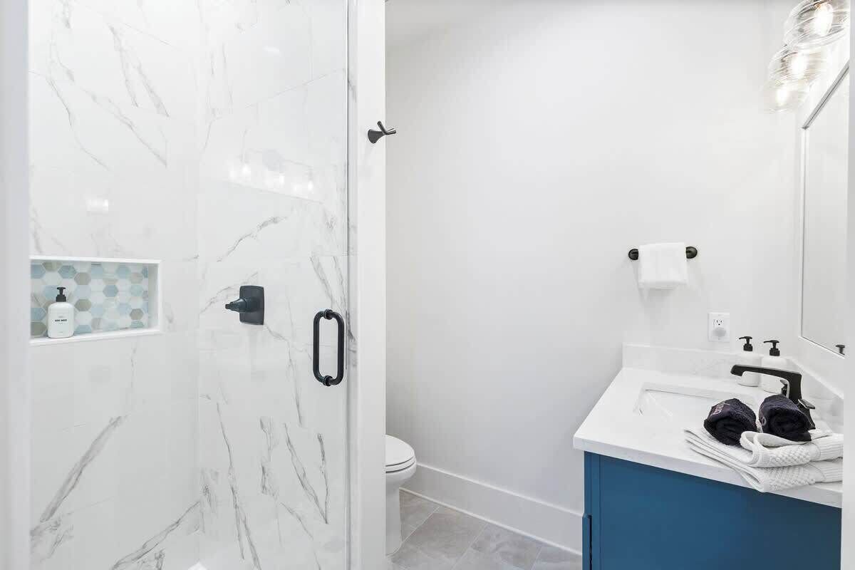 Ein Badezimmer mit Dusche, Toilette und Waschbecken inklusive Handtuchhalter.