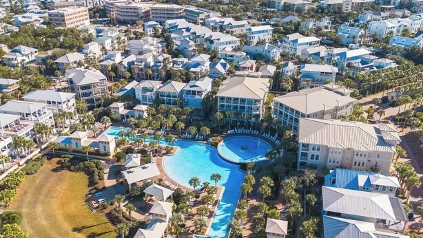 A resort with a large swimming pool, multiple buildings, and palm trees.