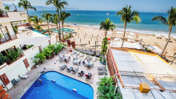 Un hotel con piscina, vistas a la playa y zona de estar al aire libre.