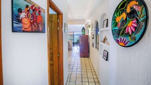 Un pasillo con piso de baldosas, una puerta de madera y un muro con dos obras de arte enmarcadas.