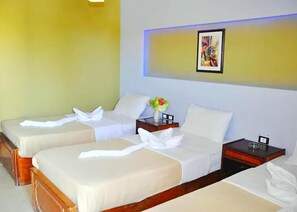 A hotel room with two beds, each with white linens and towels, a small bedside table with a vase of flowers, and a framed picture on the wall. - Geisum Beach Hotel Hurghada Red Sea (Hurghada)