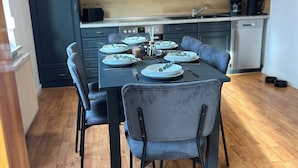 A dining area with a dark blue table set for six, surrounded by matching chairs. - Vacation home Friesenkoje, in Loquard near Greetsiel and Emden, dogs allowed (Krummhörn)
