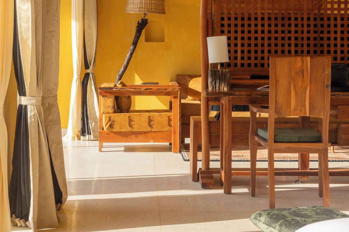 Une pièce avec un canapé en bois, une table en bois, une lampe et un ventilateur de plafond.