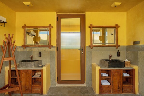 Un baño con dos lavabos, armarios de madera y un espejo.