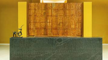 A reception desk with a carved wooden panel and a metal sculpture.