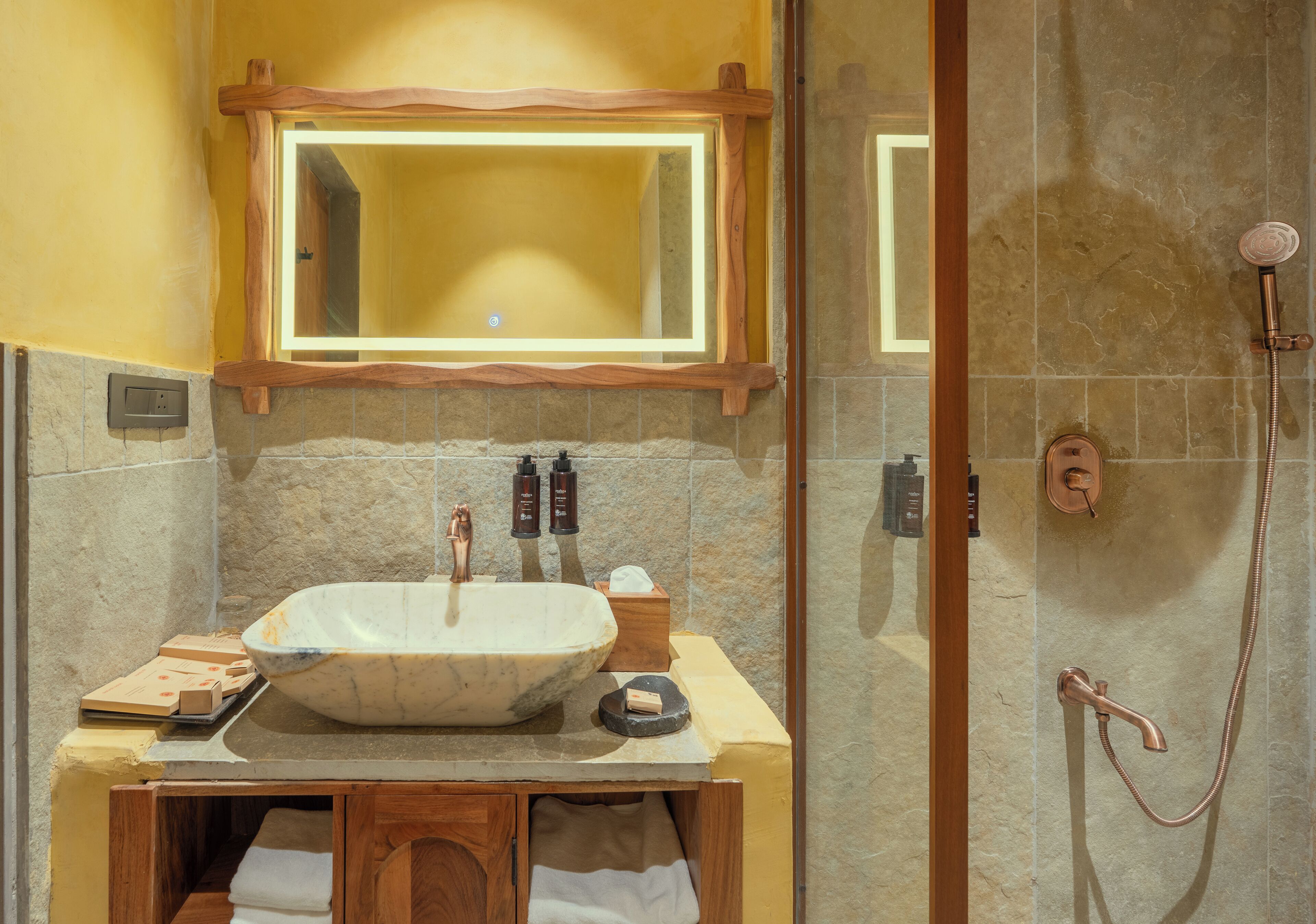 A bathroom with a large marble sink, wooden vanity, and a glass-enclosed shower area.