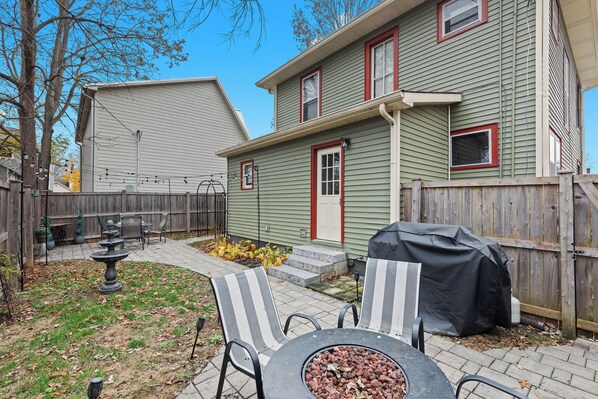 A backyard with a patio, outdoor seating, a fire pit, and a wooden fence.