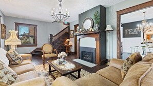 Una sala de estar acogedora con chimenea, asientos cómodos y una escalera que sube a otro nivel.
