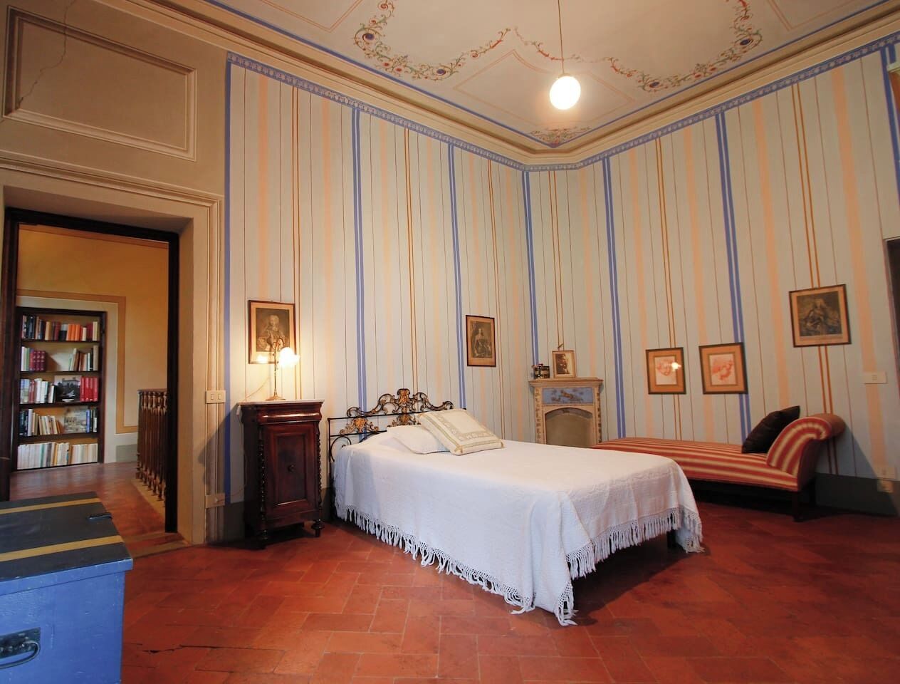 Um quarto com cama, mesa de cabeceira, cômoda e estante.