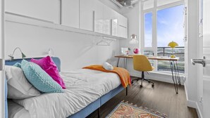Een moderne slaapkamer met een bed, een bureau en een raam met uitzicht.