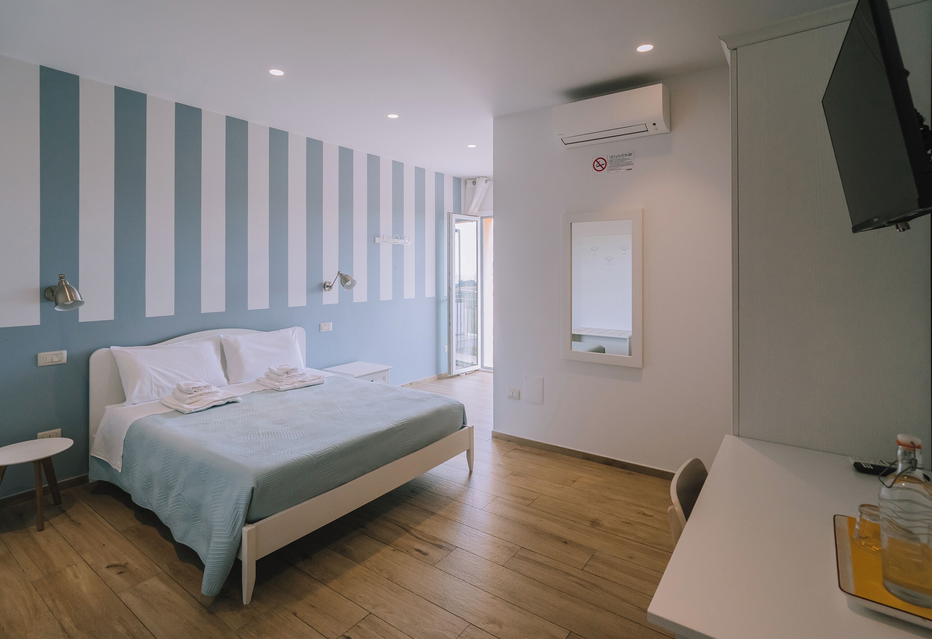 A bedroom with a bed, bedside tables, a desk, and a chair.