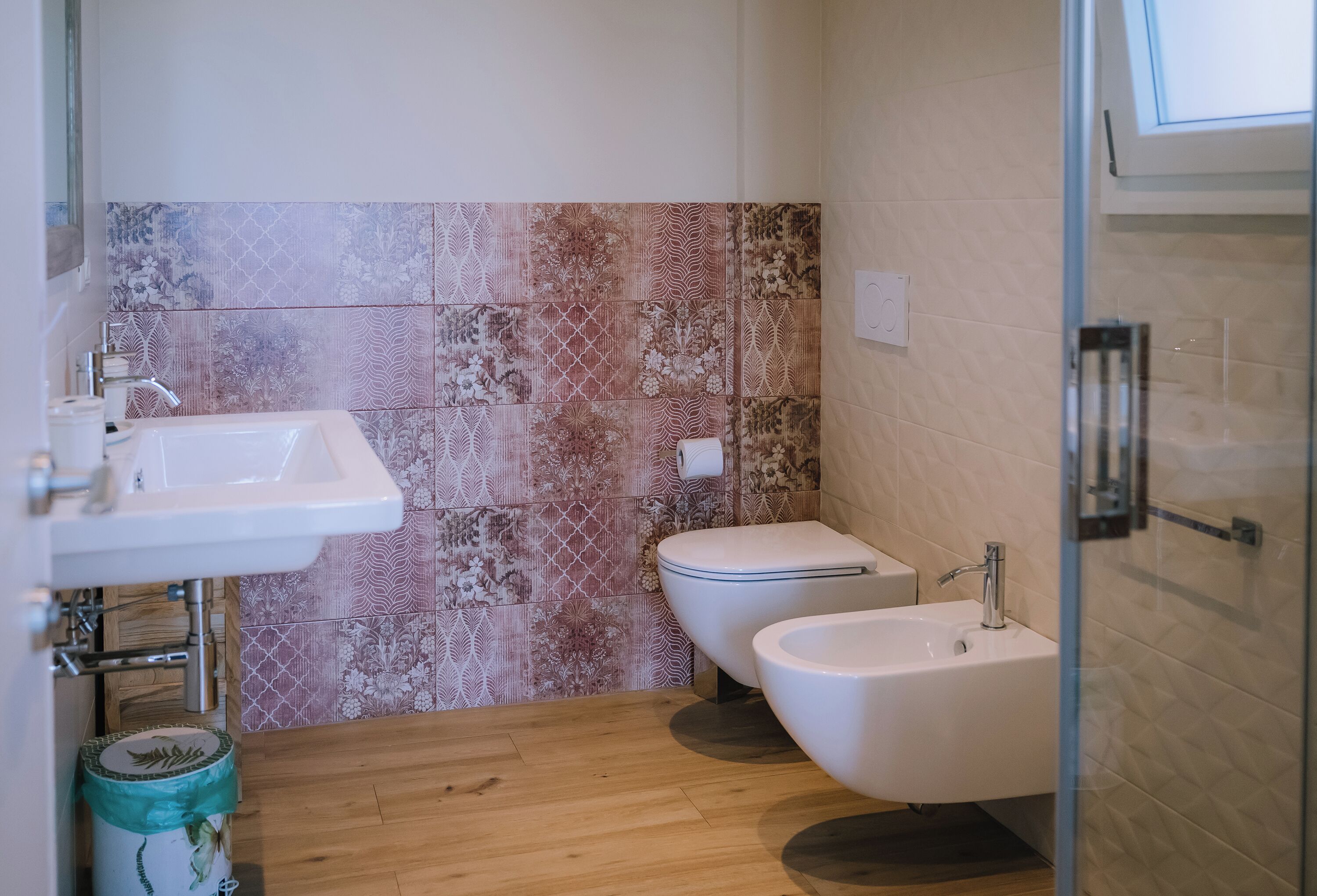 A bathroom with a sink, toilet, bidet, and a shower area.