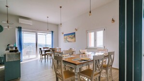 Un vaste espace dédié à la salle à manger, avec une grande table et des chaises, un comptoir de cuisine et une vue dégagée grâce à de grandes fenêtres.