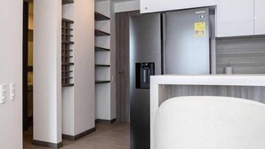 Une cuisine moderne dotée d’un réfrigérateur encastré, d’un meuble en bois et d’un plan de travail blanc.