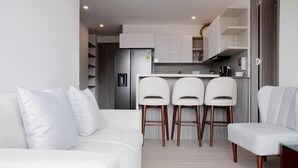 Un salon moderne avec un canapé blanc et trois tabourets de bar blancs.
