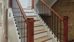 Un escalier avec des rampes en bois et des balustres noires, menant à un niveau inférieur.