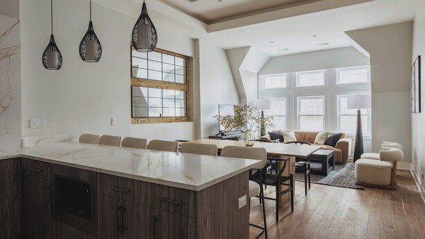 Une cuisine spacieuse dotée d’un grand îlot central, de meubles en bois et de luminaires suspendus.