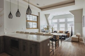 Een ruime keuken met een groot eiland, houten kastjes en hanglampen.