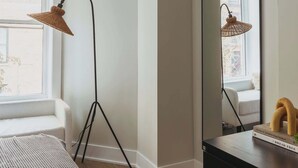Une chambre à coucher avec un lit, une commode, un miroir et une lampe sur pied.