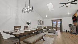 A modern living room with a dining area, a fireplace, and a television. - Hot Tub - King Suite - Game Room - Large Groups (Sun Prairie)