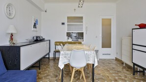 A compact living space with a dining table, chairs, a sofa, a kitchenette, and a clock on the wall. - Apartment in Blankenberge With Sea Views (Blankenberge)