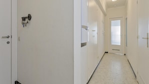 A corridor with white walls, a tiled floor, and doors on both sides. - Apartment in Blankenberge With Sea Views (Blankenberge)