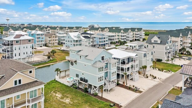 A coastal residential area with multiple two-story houses, a marina, and a view of the ocean. - Experience luxury at Salt and Light in Ocean Isle Beach, perfect for 24 guests! (Ocean Isle)