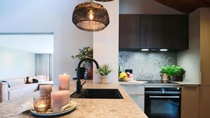 A modern kitchen with a marble countertop, a hanging light fixture, and a built-in oven. - Dune Lagoon (Egmond aan den Hoef)