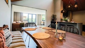 A spacious dining area with a long wooden table, woven placemats, and a candle centerpiece. - Dune Lagoon (Egmond aan den Hoef)