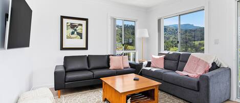 A modern living room with two sofas, a coffee table, and a large window offering a scenic view.