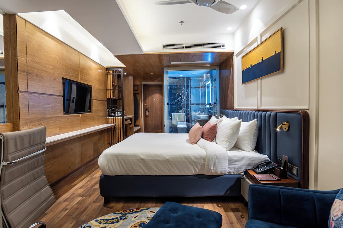 A modern hotel room with a large bed, a desk, and a seating area.