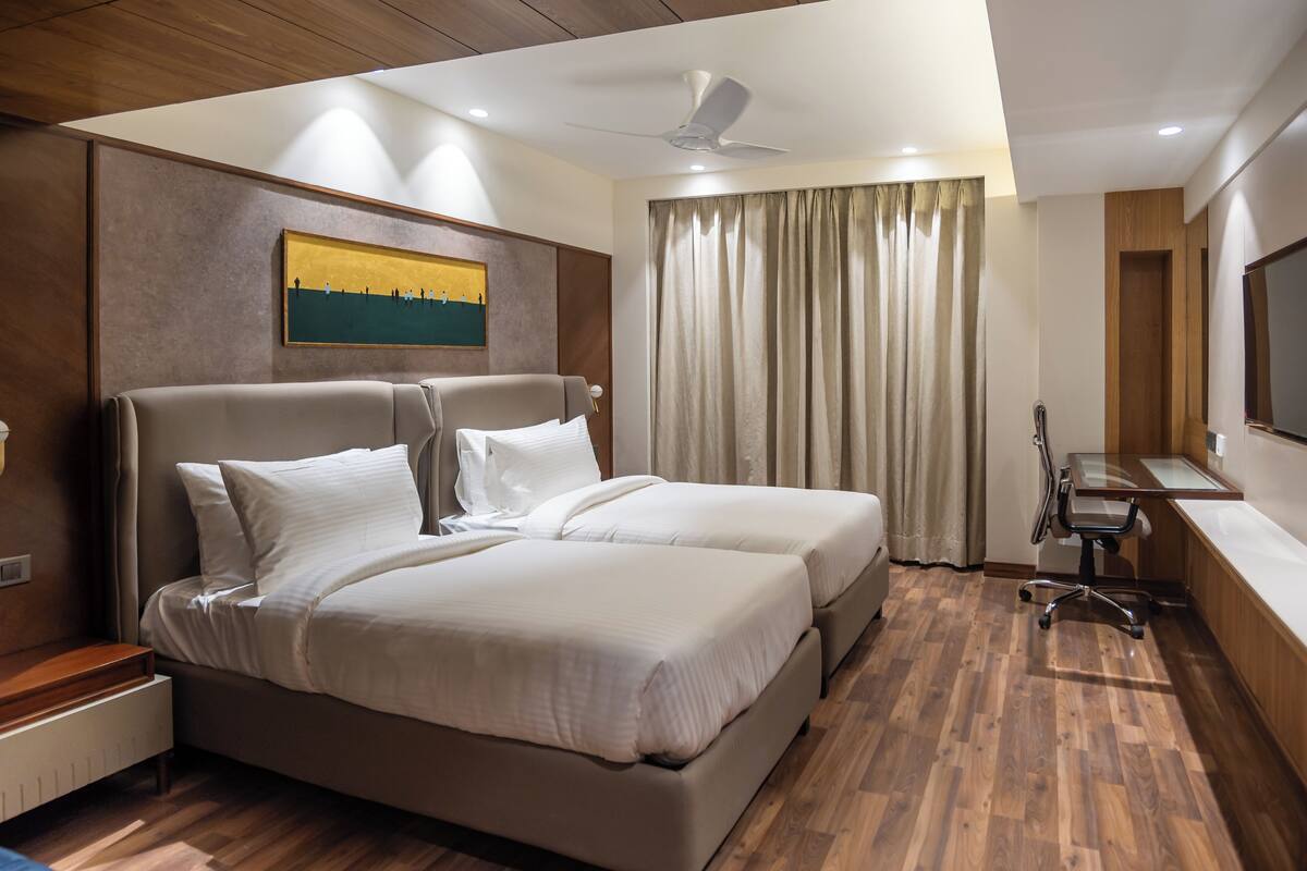 A modern hotel room with a large bed, a desk, and a television.