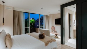 A modern hotel room with a large bed, a sitting area with a chair and table, and a view of the outdoors. - w Lotf Mountain View Low Floor (Medellín)