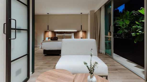 A modern bedroom with a bed, bedside table, and a large window with a view of greenery. - w Lotf Mountain View Low Floor (Medellín)