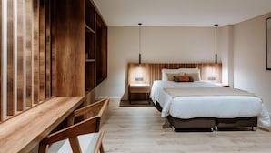 A modern bedroom with a wooden desk, a large bed, and two bedside tables with lamps. - w Loft Estandar (Medellín)