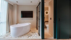 A modern bathroom with a freestanding bathtub, a toilet, and a shower area. - w Loft Estandar Plus (Medellín)